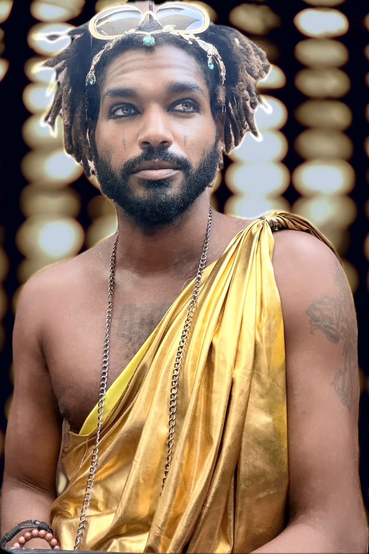Hollywood Zeus draped in a gold toga beneath a wall of stage lights